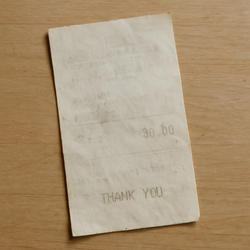 Paper receipt with faded text lying on a table